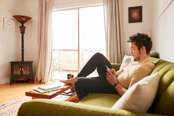 istock Young man wearing pajamas texting on his sofa in the morning 1369391341