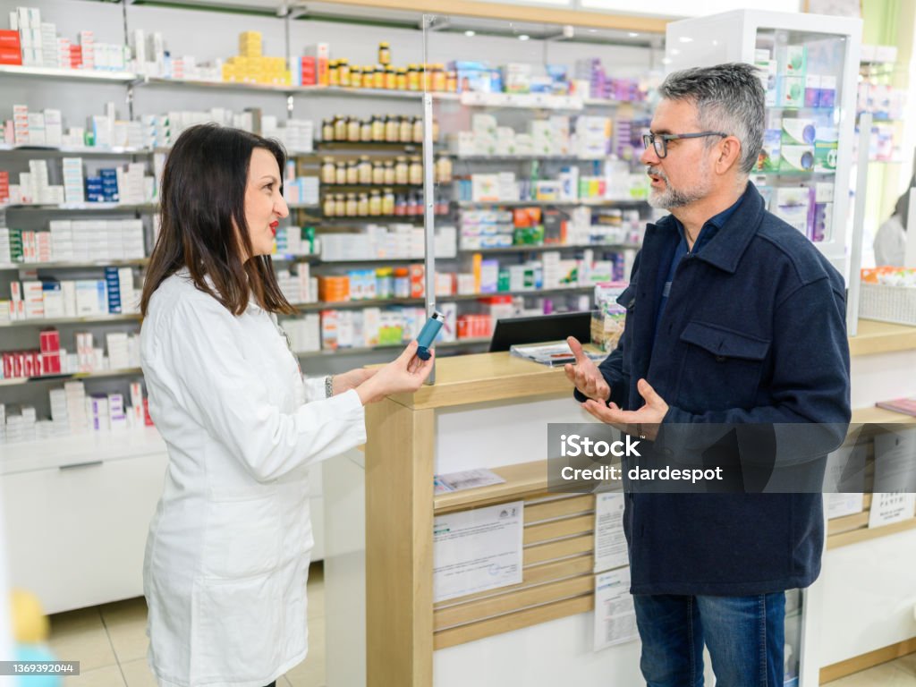 Help from a pharmacist. Help from a pharmacist. A female pharmacist holds an asthma inhaler and instructions for use. Asthma Inhaler Stock Photo