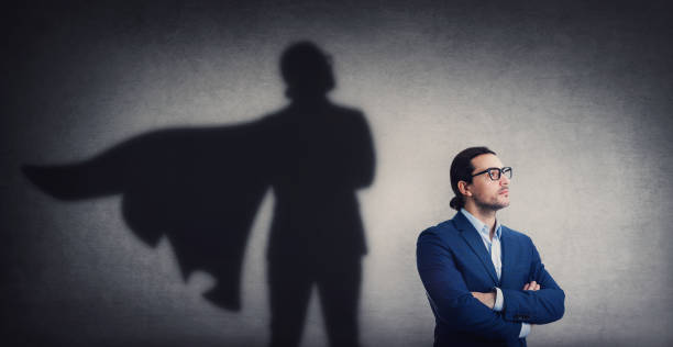 istock Confident businessman looking determined as casting a powerful superhero shadow on the wall. Motivated and ambitious business person shows inner strength. Hero leadership and power concept 1369393572