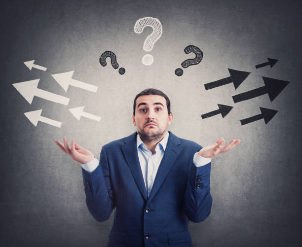 istock Perplexed businessman shrugs shoulders, hands outstretched, has doubts to choose left or right side. Puzzled male express uncertainty, has questions as different arrow points opposite directions 1369393633