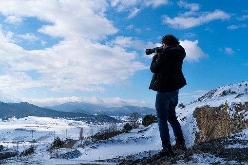 kar manzarası çeken doğa fotoğrafçısı. karla kaplı dağlık arazi ve mavi gökyüzü görüntüsü full frame makine ile çekilmiştir.