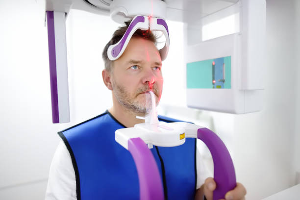 mężczyzna pacjent podczas panoramicznej radiografii w klinice stomatologii. nowoczesny sprzęt dentystyczny - x ray equipment x ray machine radiation zdjęcia i obrazy z banku zdjęć