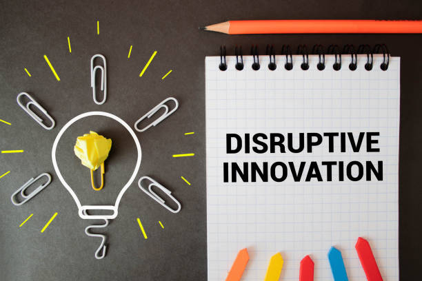 istock inscription DISRUPTIVE INNOVATION on a notepad next to a calculator, pen and charts 1369398524