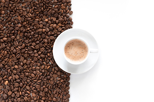 Cup of aromatic coffee and coffee roasted beans isolated on white background, top view.