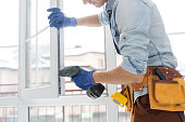 istock Construction worker installing window in house. Handyman fixing the window with screwdriver 1369399520
