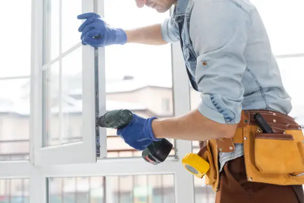 Photo of Construction worker installing window in house. Handyman fixing the window with screwdriver