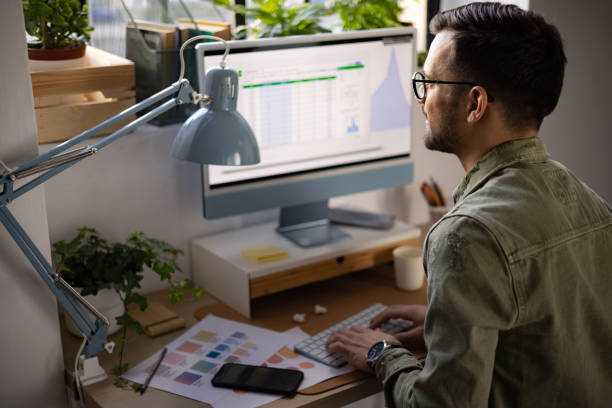 istock Rear view of a young Caucasian man working from home using a desktop pc 1369401267