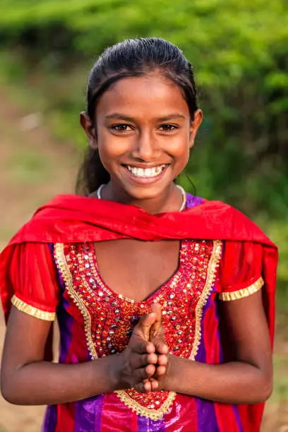Portrait of Sri Lankan young girl, saying Namaste! Her parents work on this tea plantattion near Nuwara Eliya, Ceylon. Sri Lanka (Ceylon) is the world's fourth largest producer of tea and the industry is one of the country's main sources of foreign exchange and a significant source of income for laborers.
Namaste! is a form of greeting in Hindu custom and is usually spoken with a slight bow and hands pressed together, palms touching and fingers pointing upwards, thumbs close to the chest. 
.
