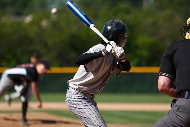 View of baseball batter from behind the catcher as they hit A batter about to hit a pitch during a baseball game. youth sports competition stock pictures, royalty-free photos & images