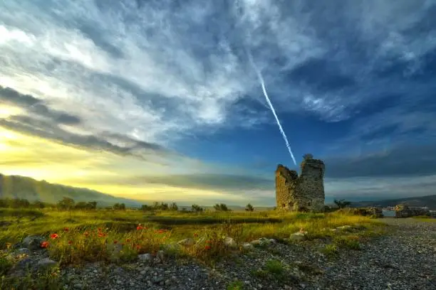 old tower ruin near starigrad croatia at sunrise with chemtrail above on meadow lighted by rising sun