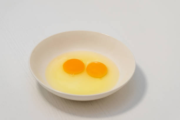 istock Two raw chicken eggs on on a white plate. Two raw egg yolks in a plate and around it is white. 1369411010