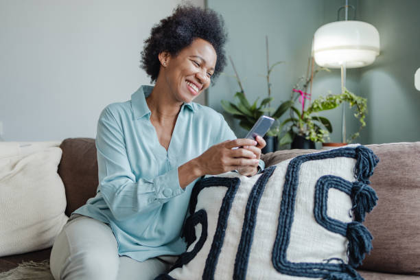 istock African-American woman using mobile phone at home and smiling 1369411182