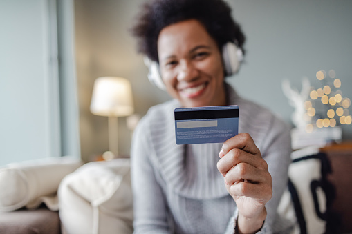 A woman is holding a credit card and looking at the camera