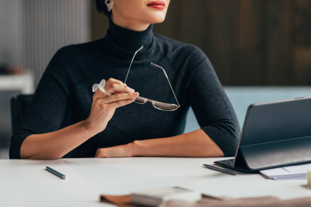istock Anonymous Businesswoman Dressed in a Black Turtleneck Sweater Holding her Glasses while Working at the Office 1369414808