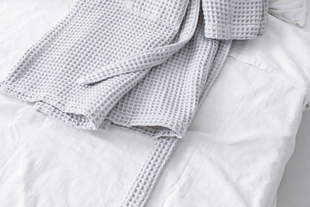 istock Clean Bathrobe on a Bed with White Sheets in a Hotel Room 1369415843