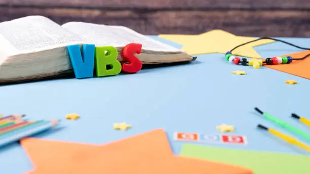 Church background with Abbreviation "VBS" (Vacation Bible School) next to black bible . Copy space text. Selective focus.