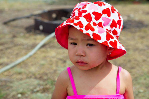 Portrait of a baby in a stroller. The child is dressed in children's overalls and a warm hat.