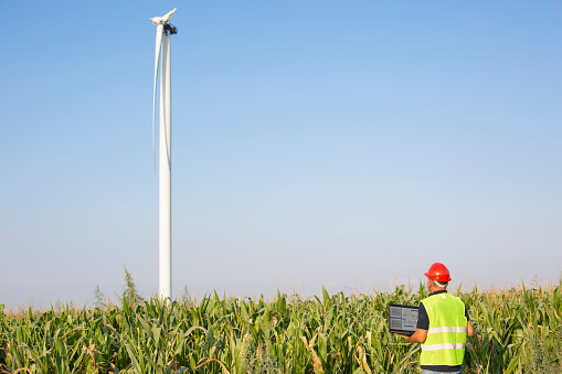 The engineer who holding laptop and looking at destroyed wind turbine