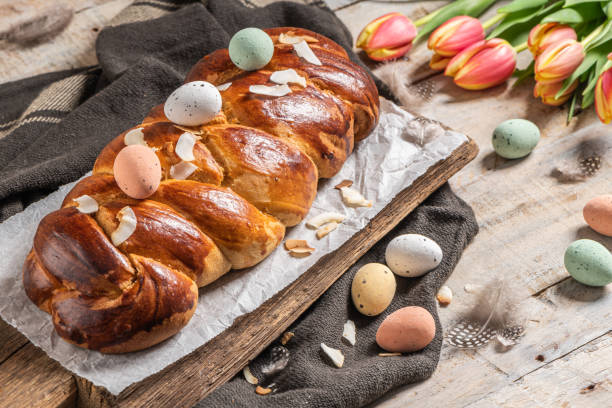 istock Portuguese traditional Easter cake. Folar with eggs on easter table. Blossom tulips, colorful painted eggs and feathers 1369430129