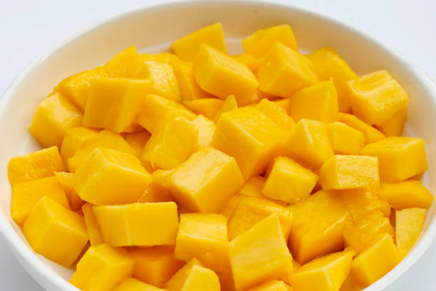istock Tropical fruit, Mango cube slices in white bowl on white background. 1369430219