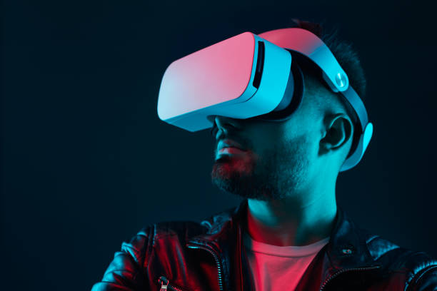 istock Man exploring virtual reality in goggles in dark room 1369437937