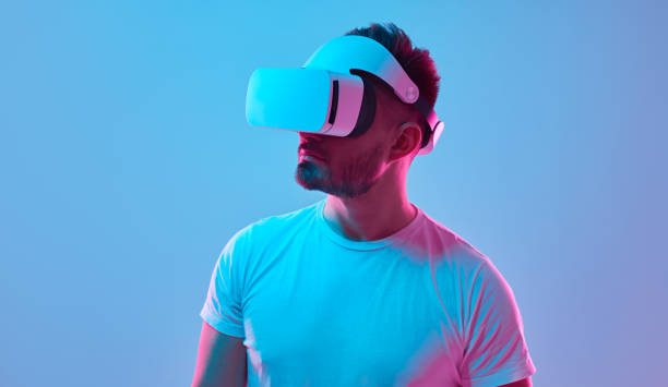 istock Man in VR headset experiencing virtual reality in studio with neon lights 1369437943