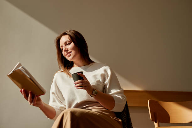 istock Woman with coffee reading book 1369437984