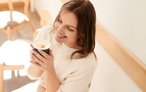 Young woman drinking coffee in cozy cafe stock photo