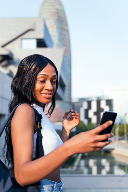 istock young black girl with backpack consulting phone 1369438019