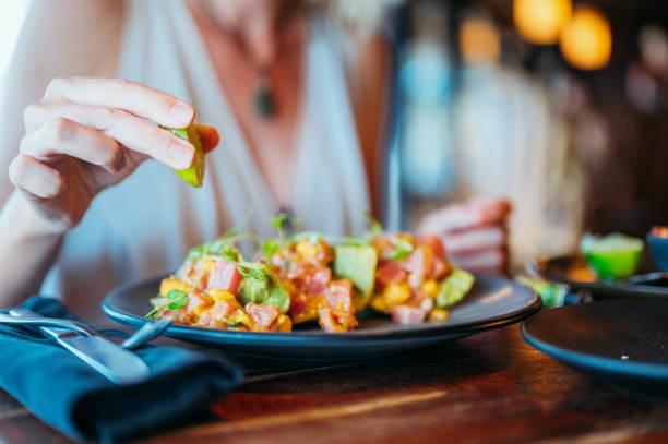 la mano de una hembra exprime un limón en sus tacos de atún - food dinner prepared fish gourmet fotografías e imágenes de stock