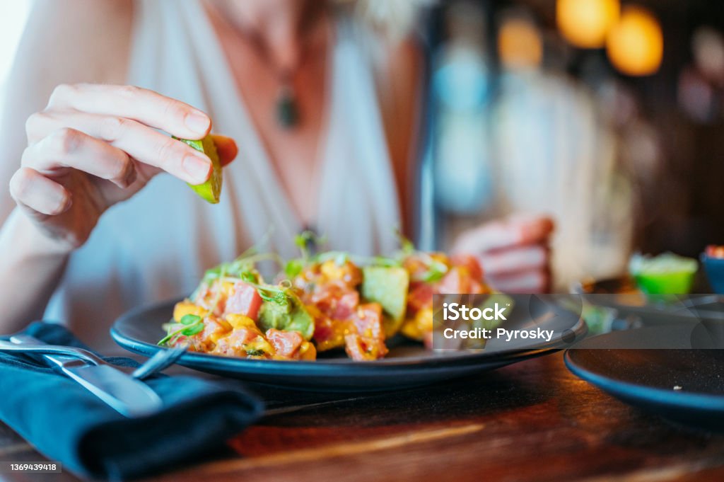 A female's hand squeezes a lemon on her tuna tacos A woman in restaurant squeezes a lime on her tuna tacos. Tuna - Seafood Stock Photo