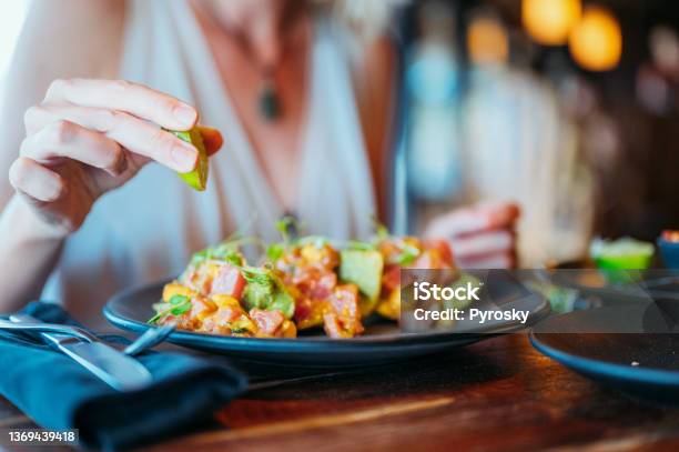 A Females Hand Squeezes A Lemon On Her Tuna Tacos Stock Photo - Download Image Now - Tuna - Seafood, Taco, Restaurant