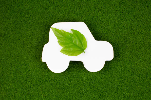 istock Close up of white car with green leaf on grass background. 1369446436