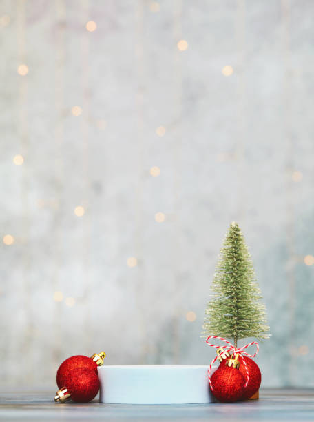maqueta navideña para producto con zócalo vacío y árbol de navidad con decoraciones rojas. espacio para el producto y el texto - christmas tree decorations indoors selective focus arrangement fotografías e imágenes de stock