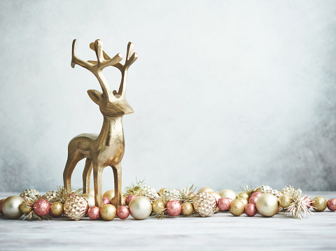 Close-up photo of funny deer figurines and a Christmas tree with bright balls. Winter composition. New Year card