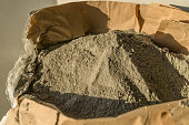 Grey sand-concrete dry mix in an open paper bag. Concrete dry powder for leveling walls and floors. Repair in the house with your own hands. DIY. Selective focus