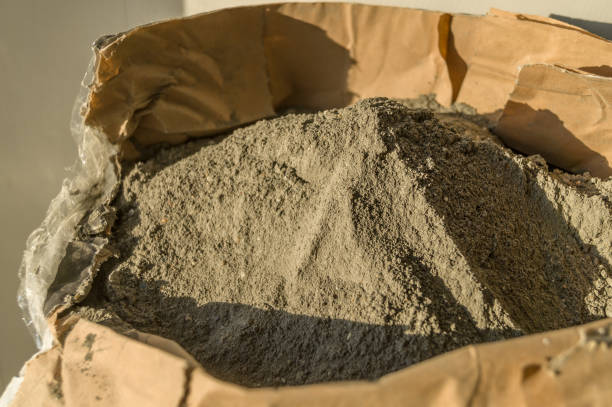 Grey sand-concrete dry mix in an open paper bag. Concrete dry powder for leveling walls and floors. Repair in the house with your own hands. DIY. Selective focus Grey sand-concrete dry mix in an open paper bag. Concrete dry powder for leveling walls and floors. Repair in the house with your own hands. DIY. Selective focus. cement bag stock pictures, royalty-free photos & images