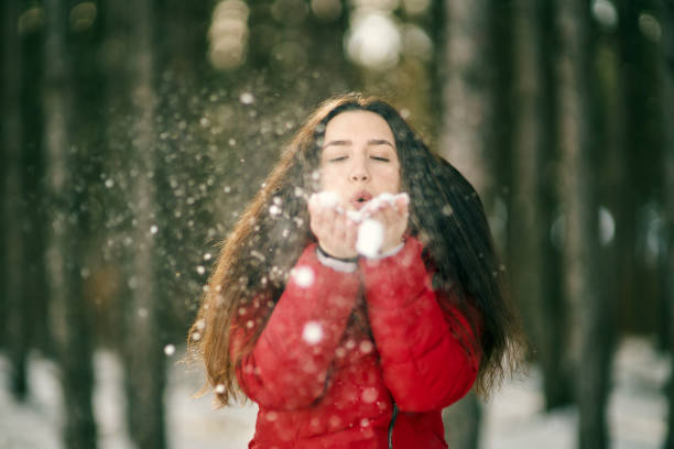 istock Young woman blowing snow in the snow forest 1369462701