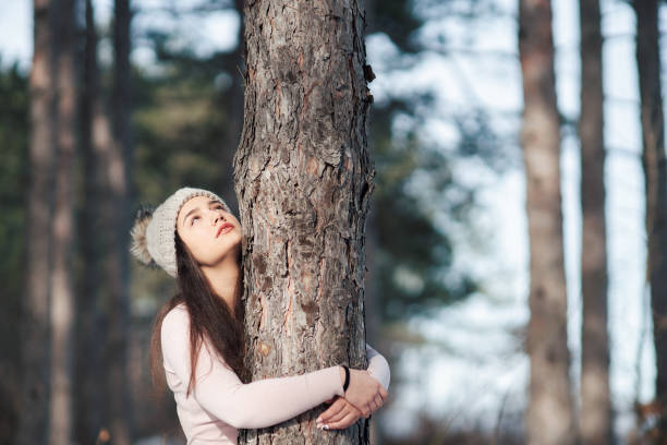 istock Young woman embracing a tree in sunny forest 1369462705
