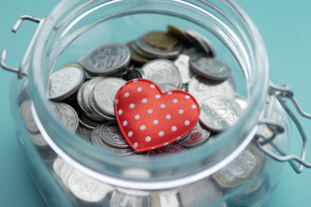 istock Red heart and coins in a jar on blue background 1369464806