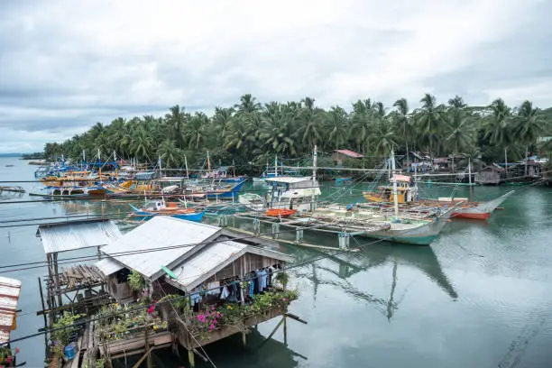 Colourful fishing boats docked peacefully near Coastway Beach, at Diatagon Village, which is a very nice and calm holidays area. 
Also you can see some surrounding picturesque floating houses. This boats are built in the same village, located at Lianga, Surigao del Sur, Mindanao Region, The Philippines.
