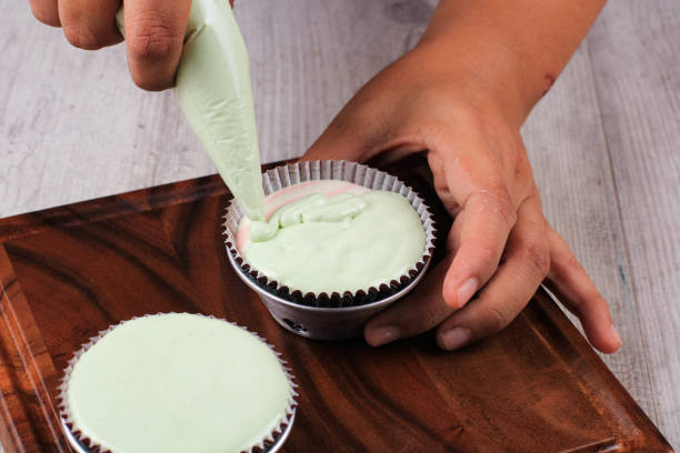 istock Female Hand Pour Green Cupcake Batter to the Mold with Beatiful Papercup, Baking Process Step by Step in the Kitchen. Making Bolu Kukus 1369470117