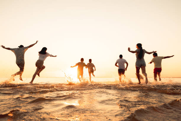 große gruppe von freunden oder große familienführung am sonnenuntergangsstrand - strandurlaub stock-fotos und bilder