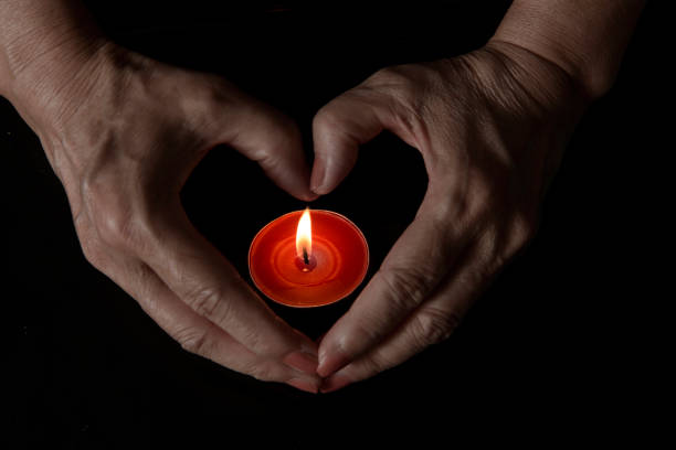 istock shapes heart with hands over burning candle on dark background 1369486041