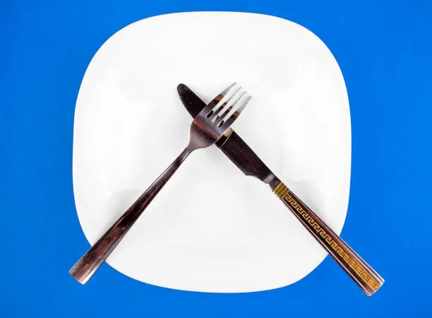 Empty Plate with a Cutlery on the Blue Paper Background