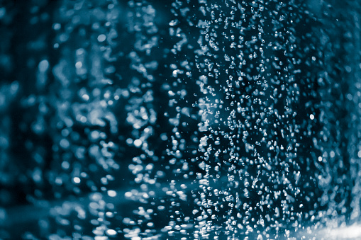 Illuminated drops of a fountain on dark blue background