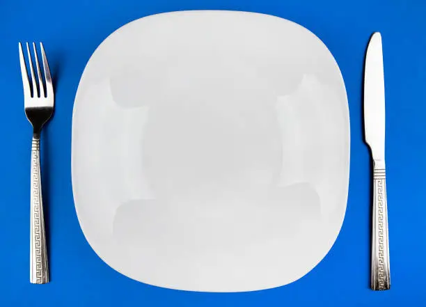 Empty Plate with a Cutlery on the Blue Paper Background