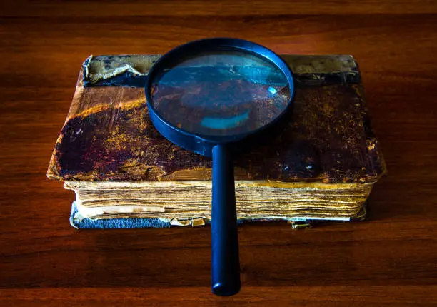 Old Book with a Magnifying Glass on the Table closeup