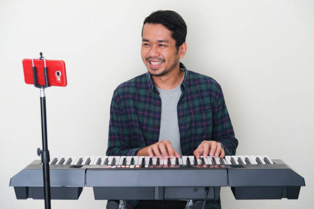 adult asian man smiling happy when learning playing piano on online course - main course imagens e fotografias de stock