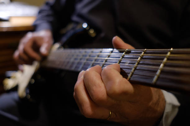 istock Old man playing guitar at home 1369496533